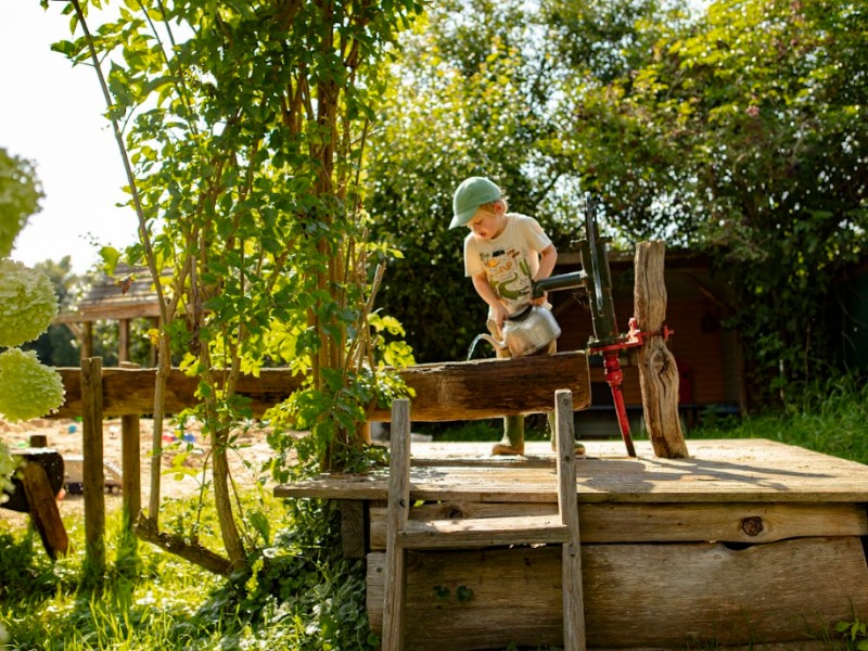 kind speelt met water bij waterpomp