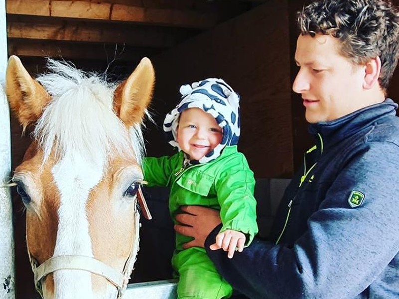 Boer Aico met zoontje Riley bij het paard