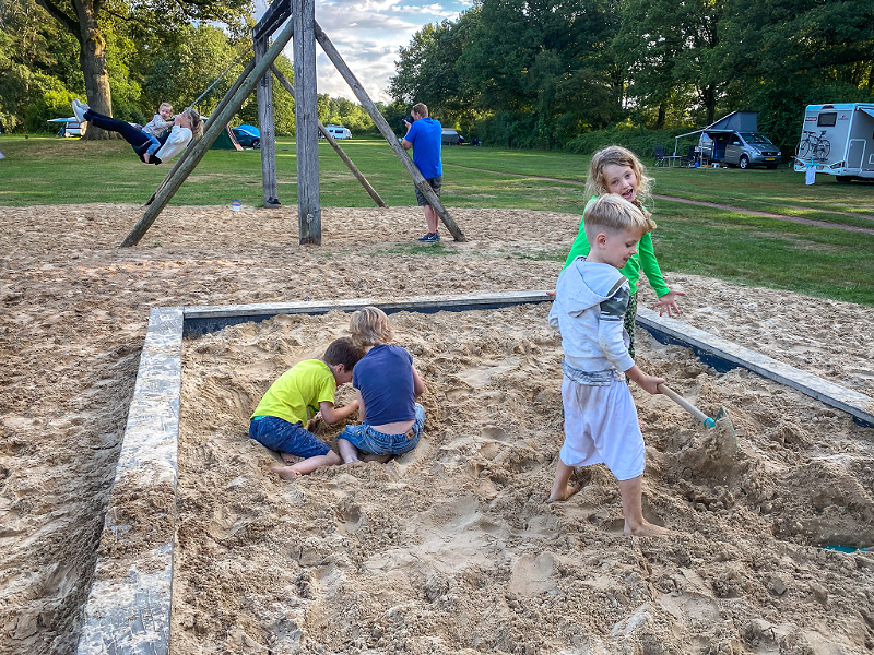 Kinderen spelen in de zandbak op een speelplekje op camping de Roos
