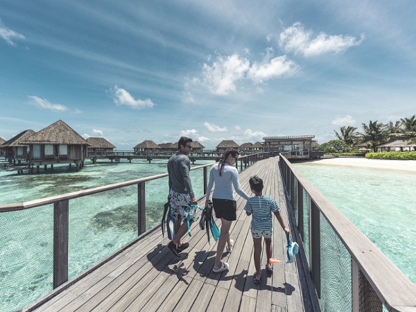 gezin wandelt over de steiger op tropisch strand