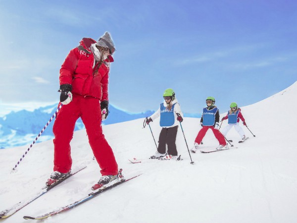kinderen skieën achter de skilerares aan