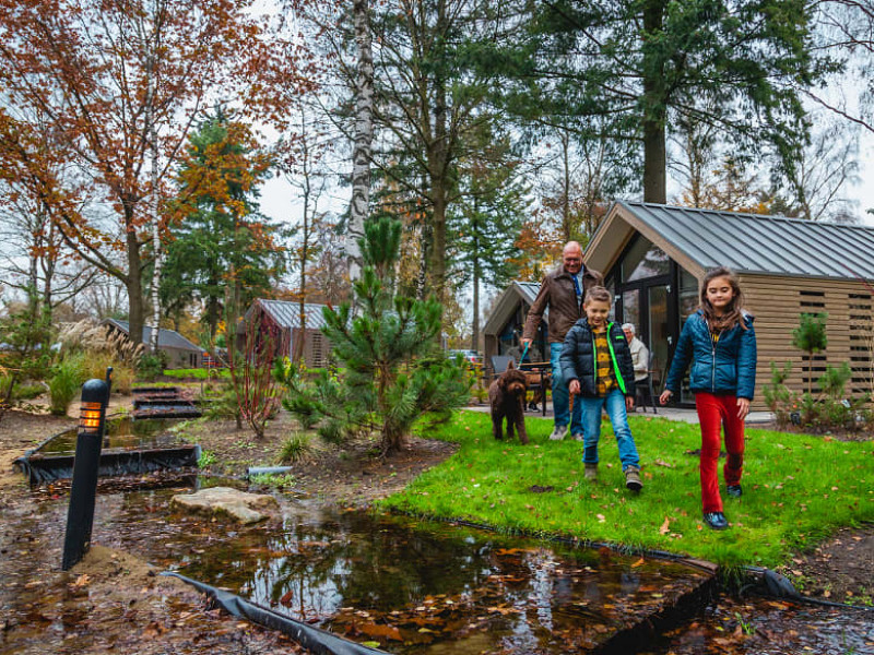 Gezin aan de wandel bij mooie chalets in een bosrijke omgeving