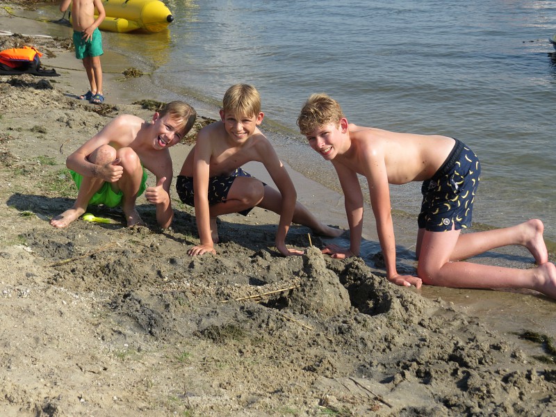 De jongens bouwen een zandkasteel op het strand van het Veluwemeer