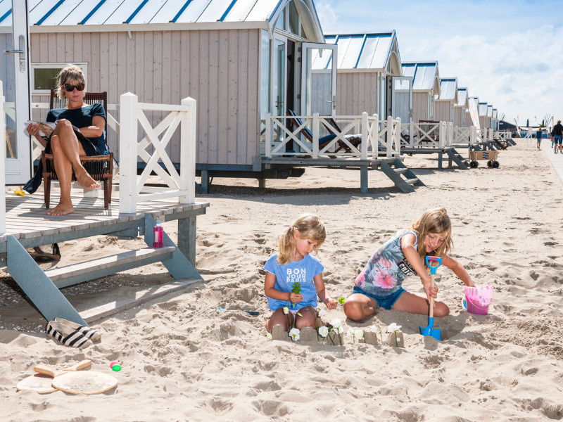 Overnachten in een Haagse strandhuisje, kids spelen voor het huisje in het zand