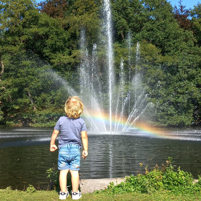Klein geluk bij een regenboog in de fontein