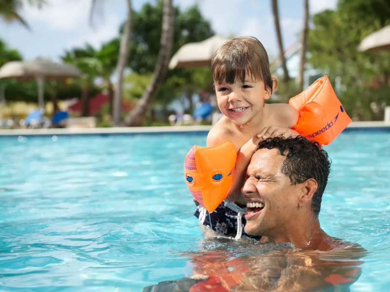 Vader en zoon hebben plezier in het zwembad van het Jan Thiel Resort