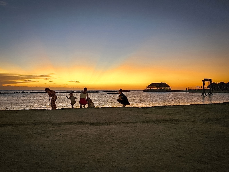 Gezin op het strand bij zonsondergang bij Mangrove Beach Resort
