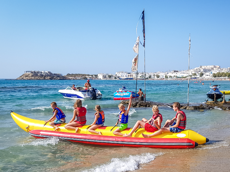 De jongens en andere kinderen op een banaan in de zee bij Naxos, Griekenland