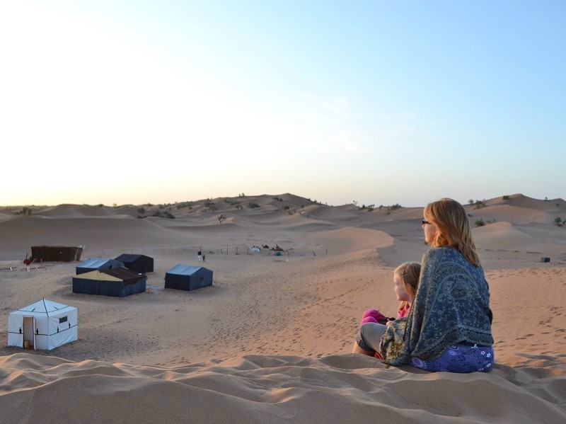 Genieten van de zonsondergang op de zandduin in Marokko