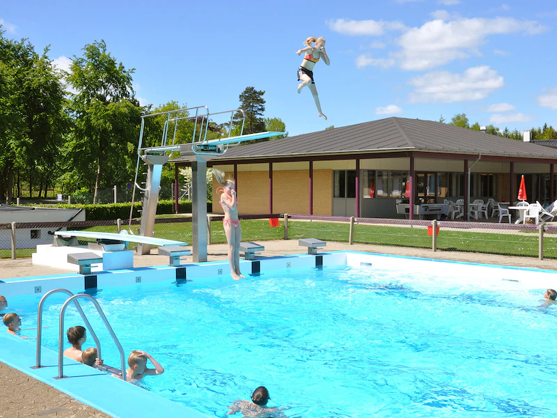 Kinderen duiken van de duikplank af het zwembad in op de Give Camping Og Cafetaria in Denemarken