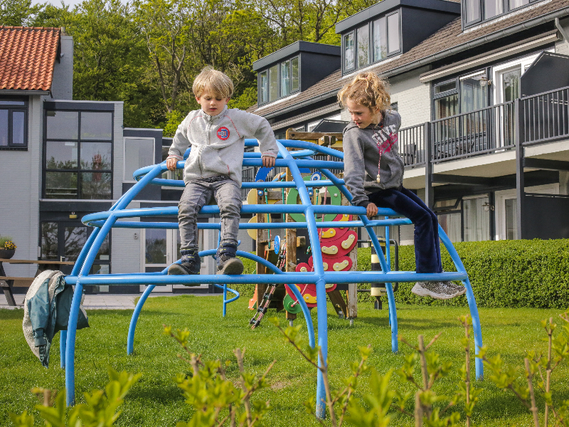 De kinderen spelen in het speeltuintje tussen de appartementen in bij Apart Hotel Bos en Duin op Texel
