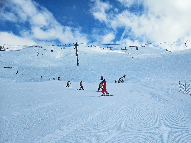 Een skiklasje komt naar beneden van de groene piste