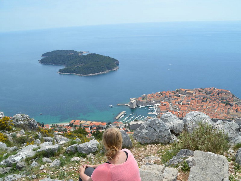 Meisje kijkt vanaf de berg op de stad Dubrovnic