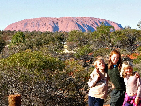 De kinderen poseren voor Uluru, oftewel Ayers Rock