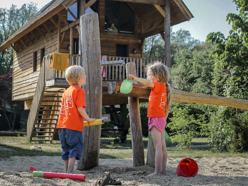Kinderen spelen in een speeltuintje voor hun vakantiehuis op vakantiepark Sandberghe in Brabant