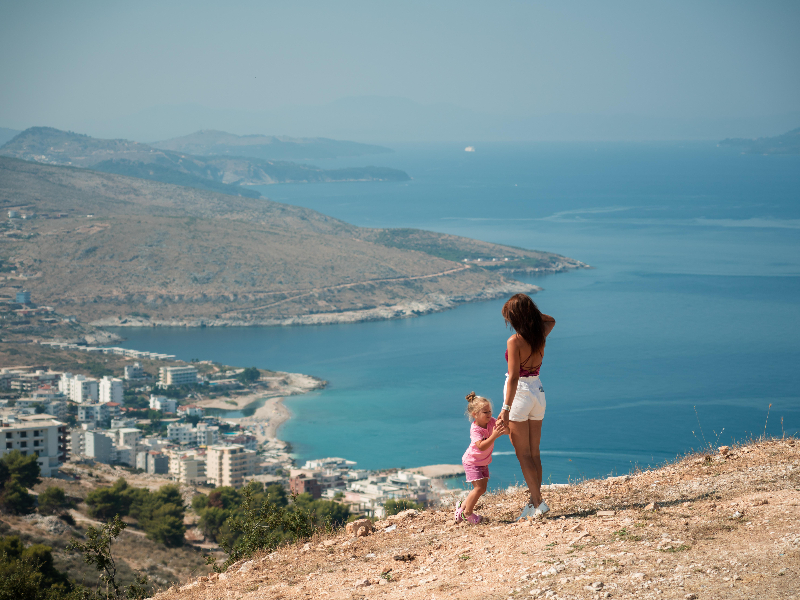 Moeder en kind kijken uit over de kustplaats Sarandë in Albanië, aan de Albanese Rivièra.