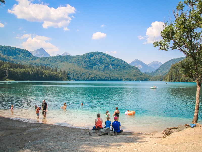 Gezin ontspant aan de helderblauwe Alpsee in Duitsland