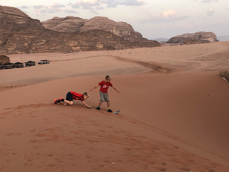 De jongens aan het sandboarden in de Jordaanse woestijn