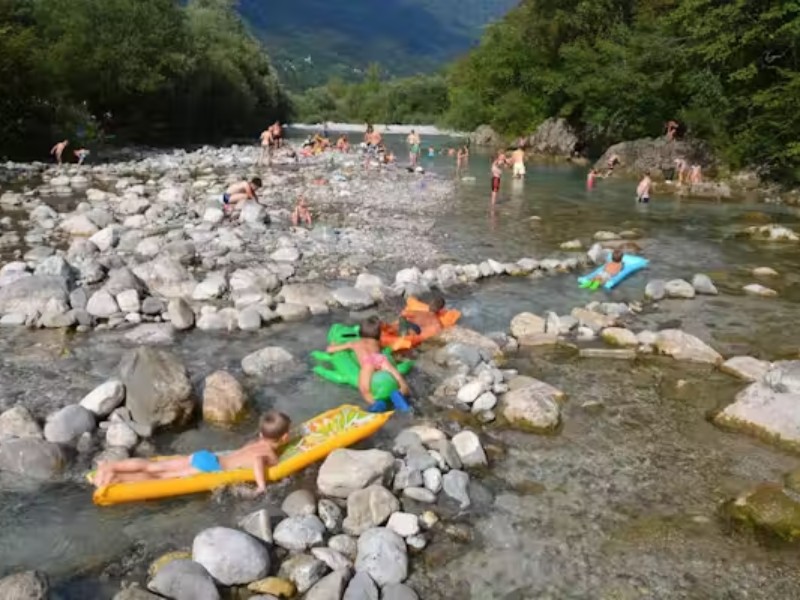 Kinderen hebben lol op de rivier Nadiza bij de Sloveense camping Nadiza Podbela