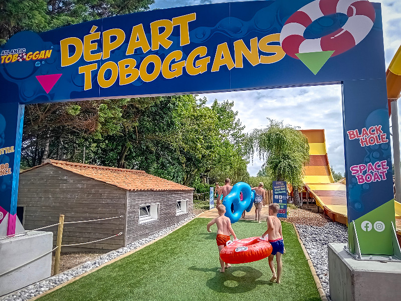 De jongens lopen met het band naar de glijbaan