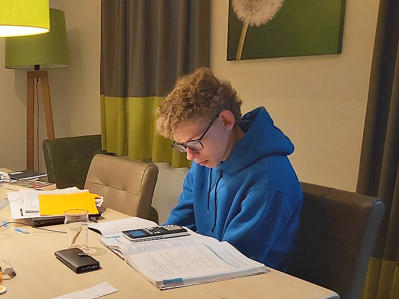 Zeb zit zijn huiswerk te maken aan de grote tafel van de hoevewoning