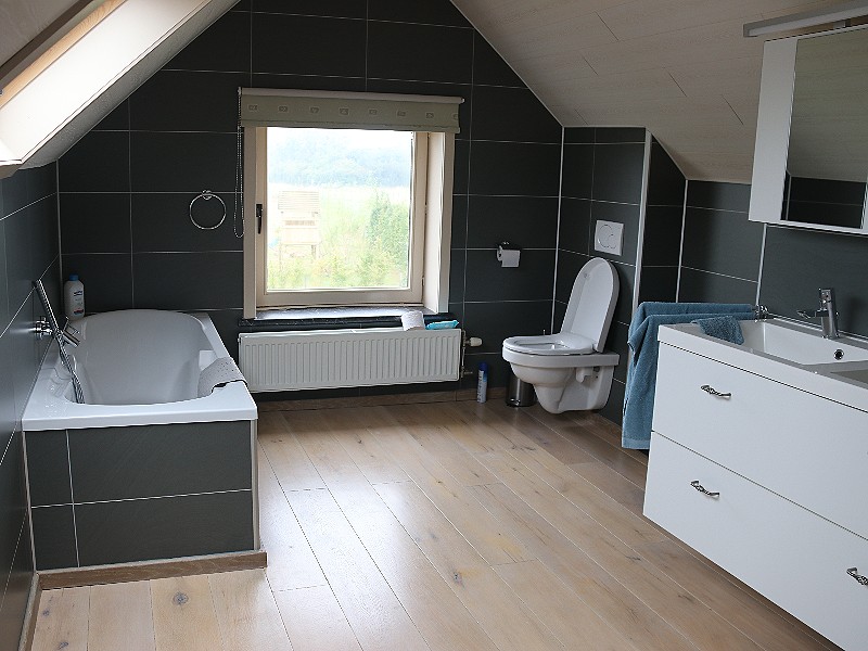 De badkamer boven met ligbad en aparte douche