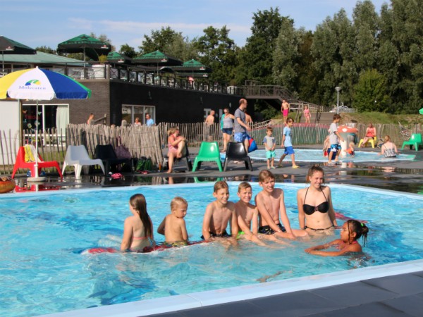 Het buiten zwembad van Molecaten Flevostrand, met op de achtergrond het terras van het restaurant