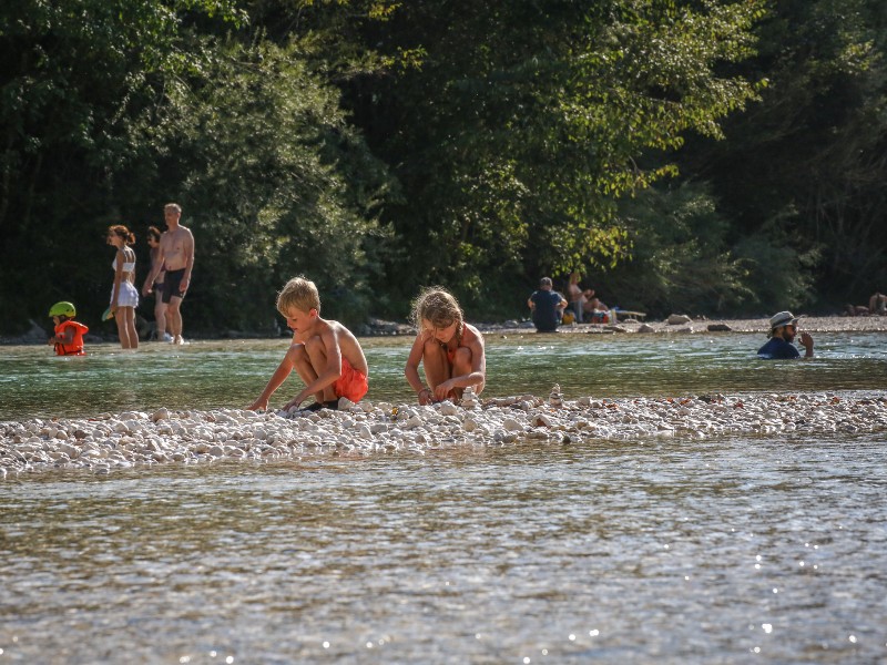 De kinderen spelen in de rivier de Soca bij het plaatsje Čezsoški