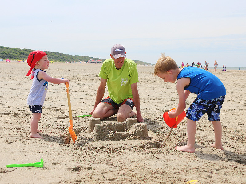 Luchtige kleding en petje tegen de zon op het strand