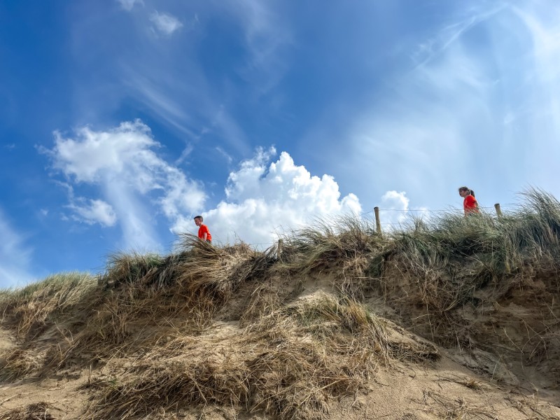 De kids lopen door de duinen. Vanaf Duinzoomhoeve is het slechts enkele minuten naar de zee!