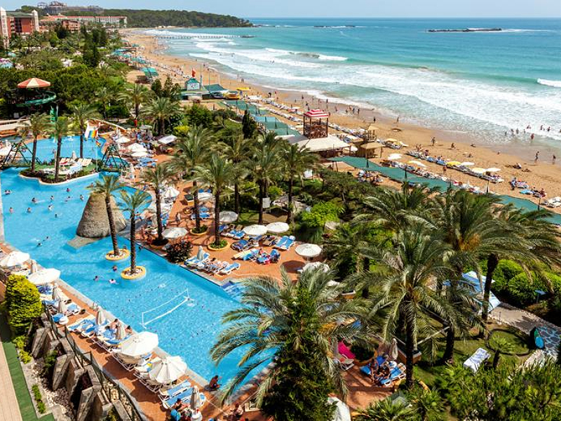 Het strand en zwembad tussen de palmbomen van Alanya