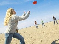 Meisje vangt frisbee op het strand