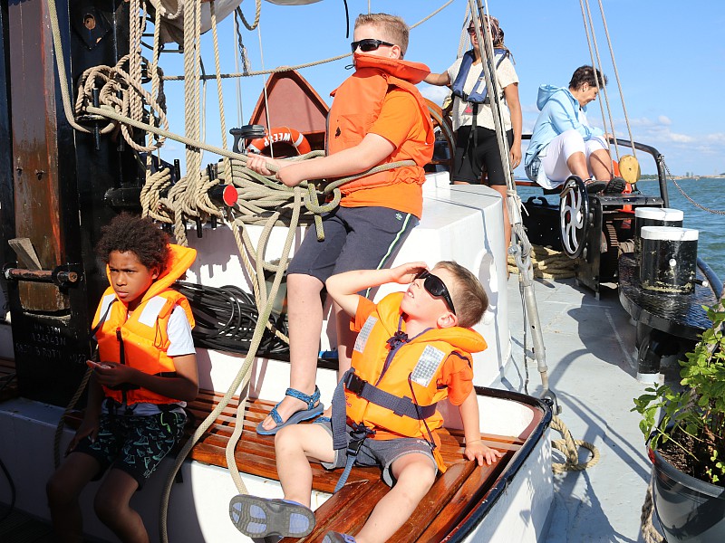 De kids helpen mee met het reilen en zeilen aan boord!