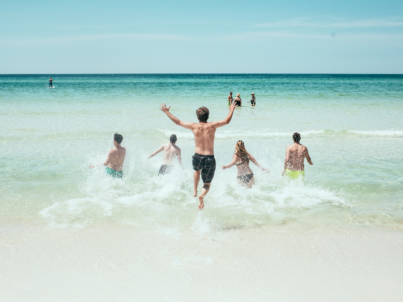 Jongeren rennen de zee in tijdens een strandvakantie.