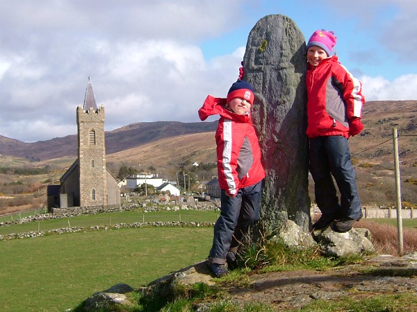 Kinderen poseren bij een religieuze steen in Glencolmcille, Donegal