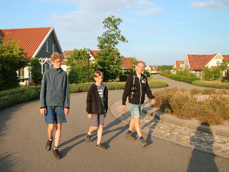 De mannen lopen langs de huisjes van residence Klein Vink