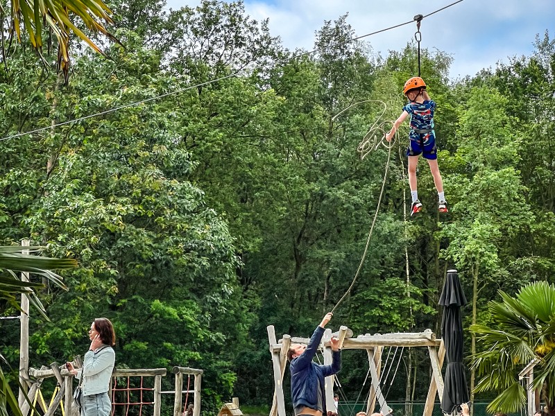 Een ouder gooit een touw naar zijn kind om haar te begeleiden aan de zipline