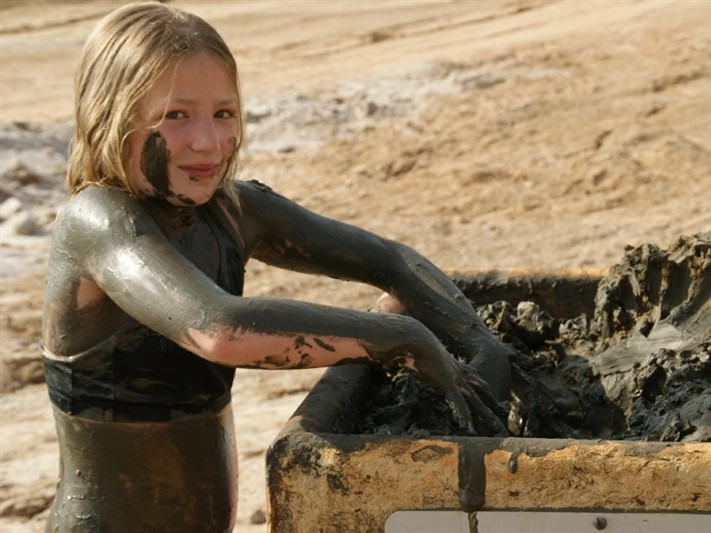 Meisje smeert zich onder de modder bij de Dode Zee