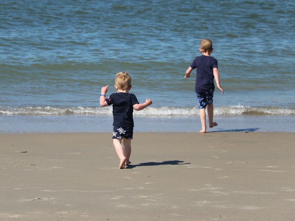 Kids rennen over het strand naar het water