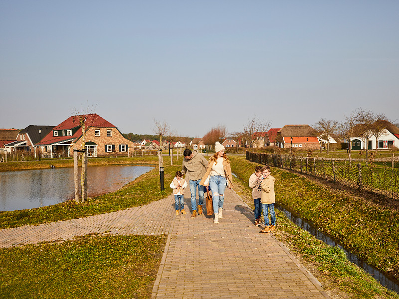 Gezin wandelt tussen de bungalows op vakantiepark de Leistert