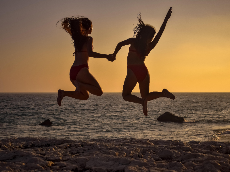 Meiden springen in de branding tijdens een tienervakantie.