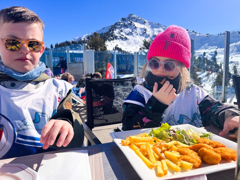 De kinderen genieten van een hapje op de piste