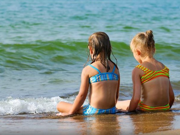 Kinderen zitten aan de rand van de Middellandse zee