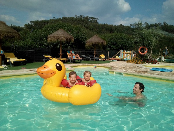kinderen vermaken zich op de opblaas eend in het zwembad