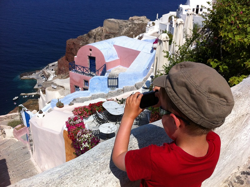 Jongentje bekijkt met de verrekijker de haven van Santorini