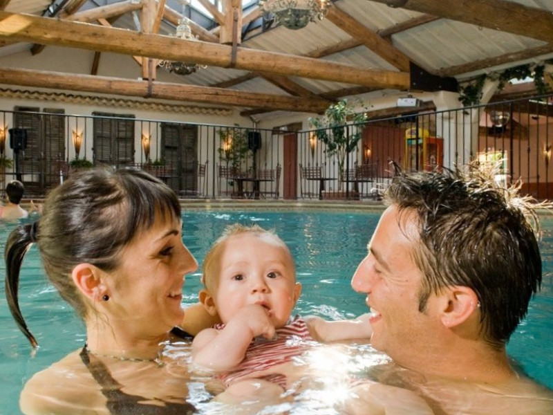 Ouders met hun baby in het zwembad op vakantie