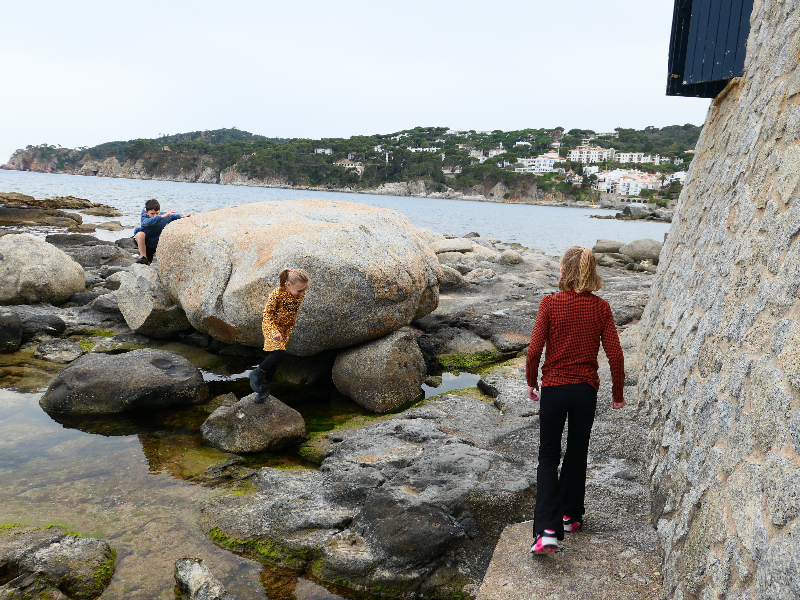 De kinderen klimmen over de rotsen naar het volgende strand