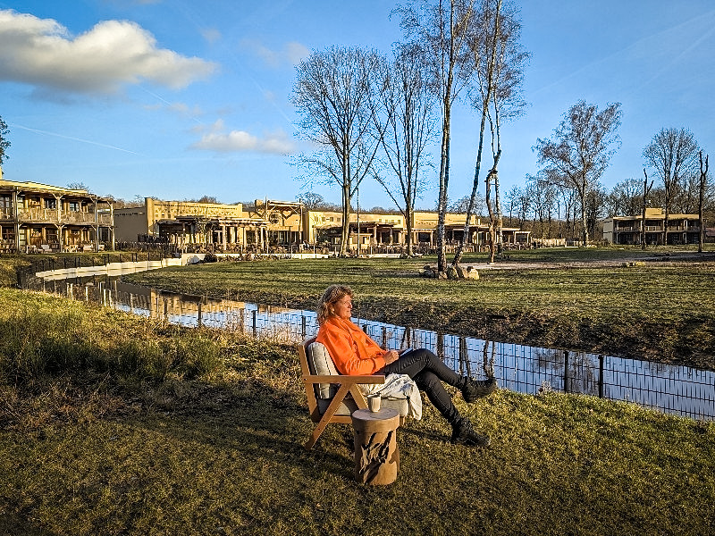 Sabine in het zonnetje voor de hotelkamer met de savanne en de hotelkamers op de achtergrond