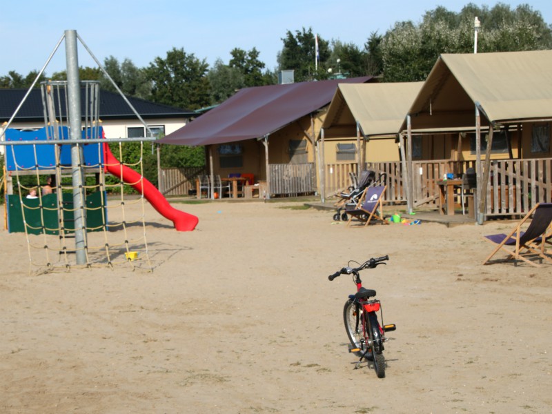 De luxe safaritenten staan aan een zand-veld