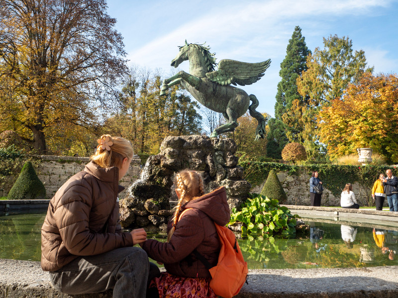 De meiden bekijken de fontein in de Mirabell-tuin